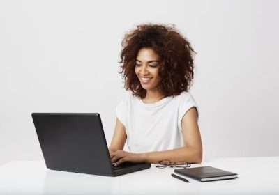 african-businesswoman-smiling-working-laptop-white-wall_176420-11190