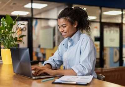 side-view-smiley-woman-working-with-laptop-office_23-2148908808